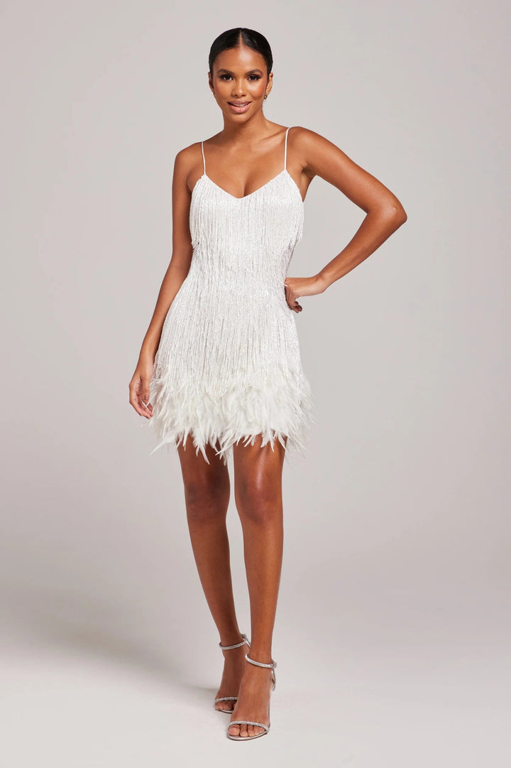 Woman wearing a white feathered dress against a plain background