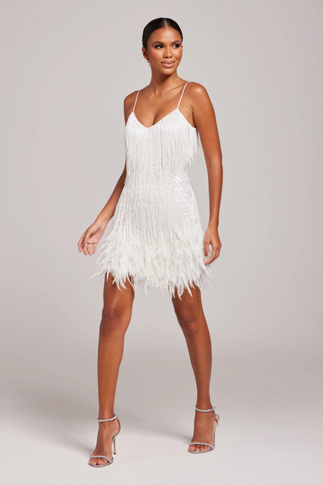 Woman wearing a white fringe dress against a plain background