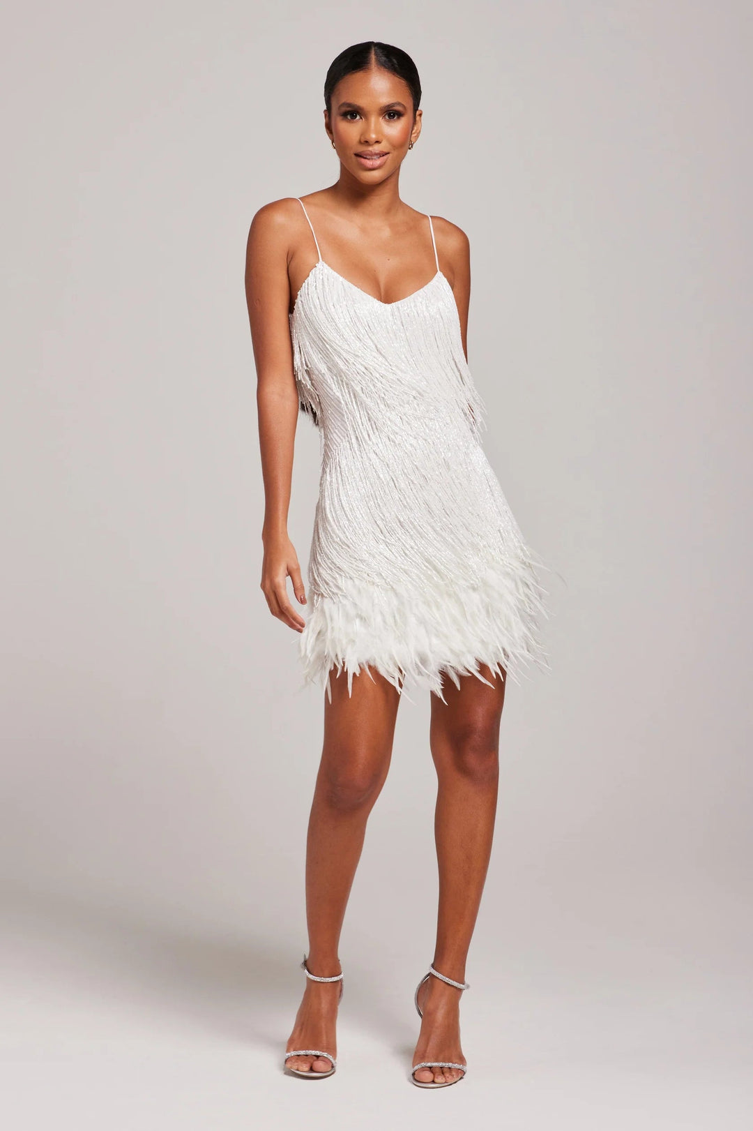 Woman wearing a white feathered dress against a plain background