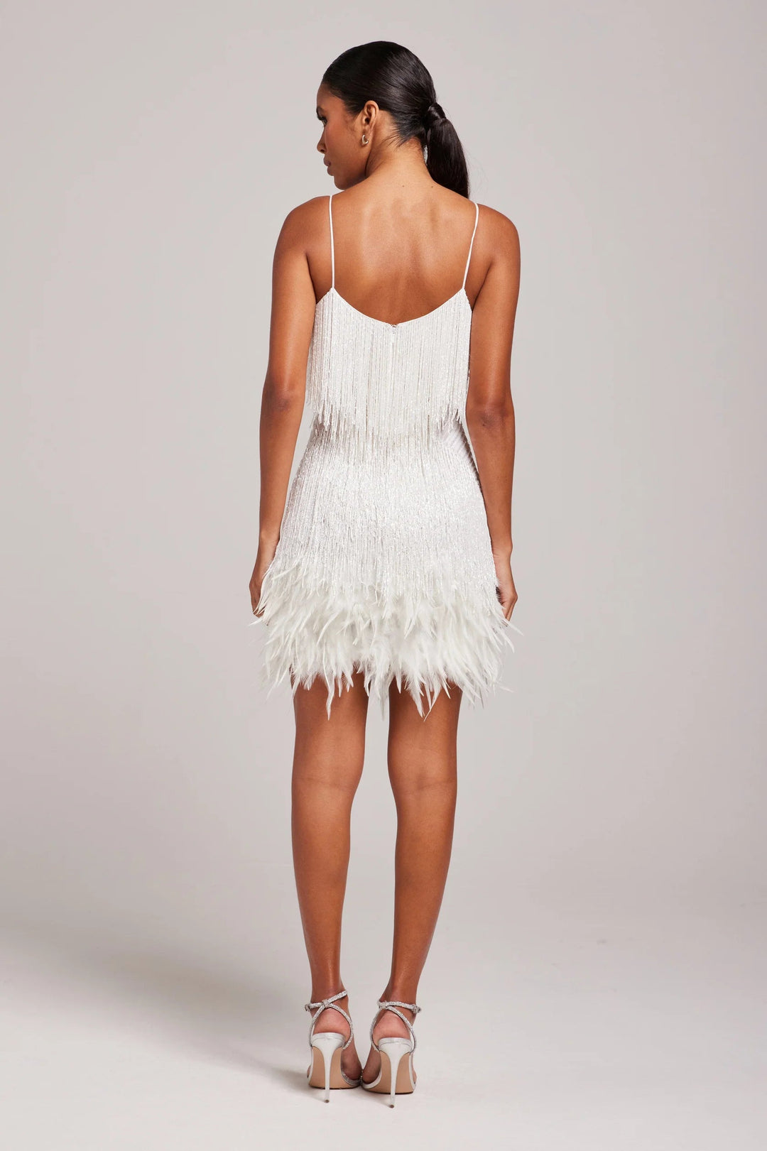 Woman wearing a white feathered dress on a plain background
